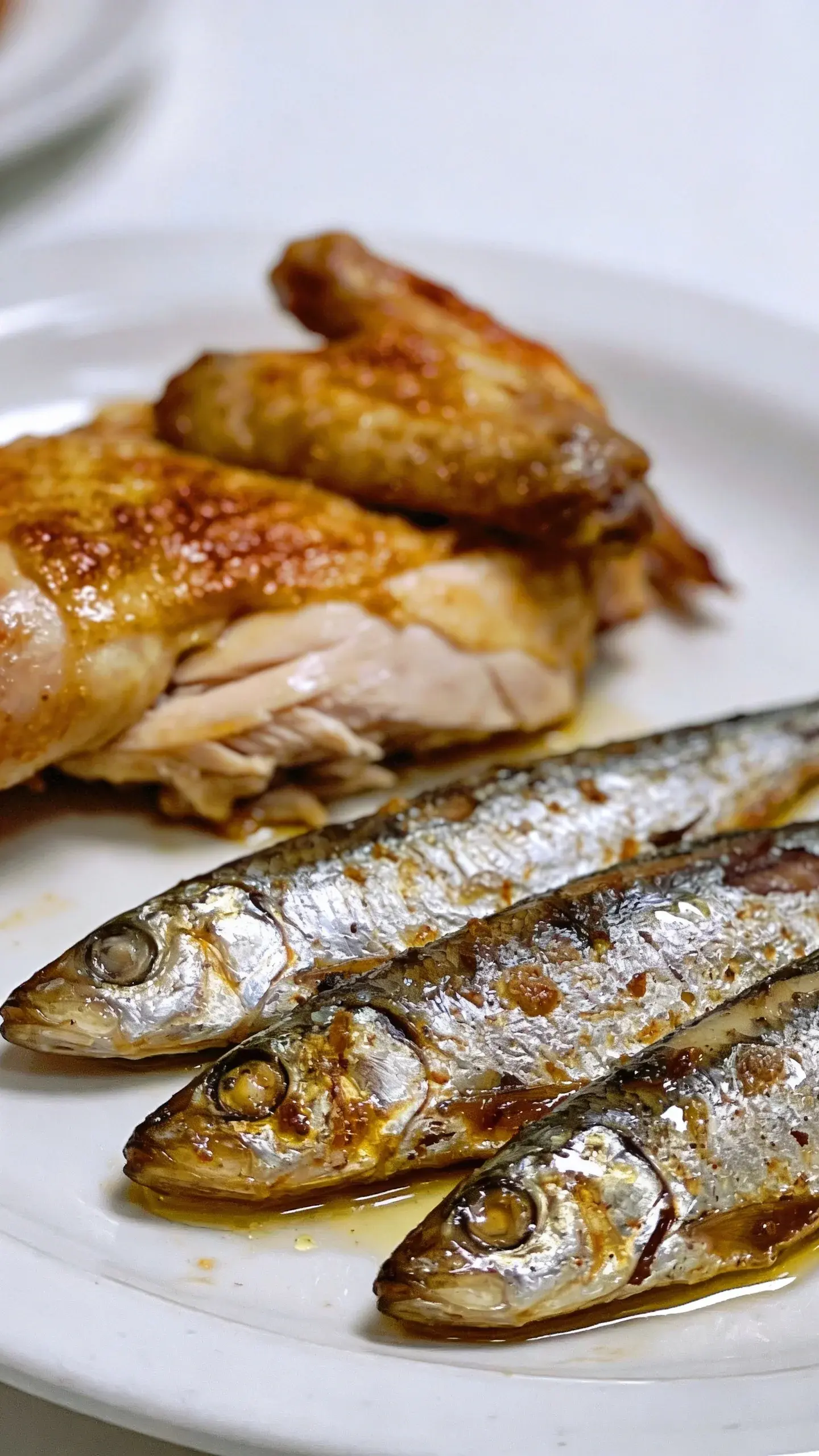 cooked chicken and sardines on white ceramic plate